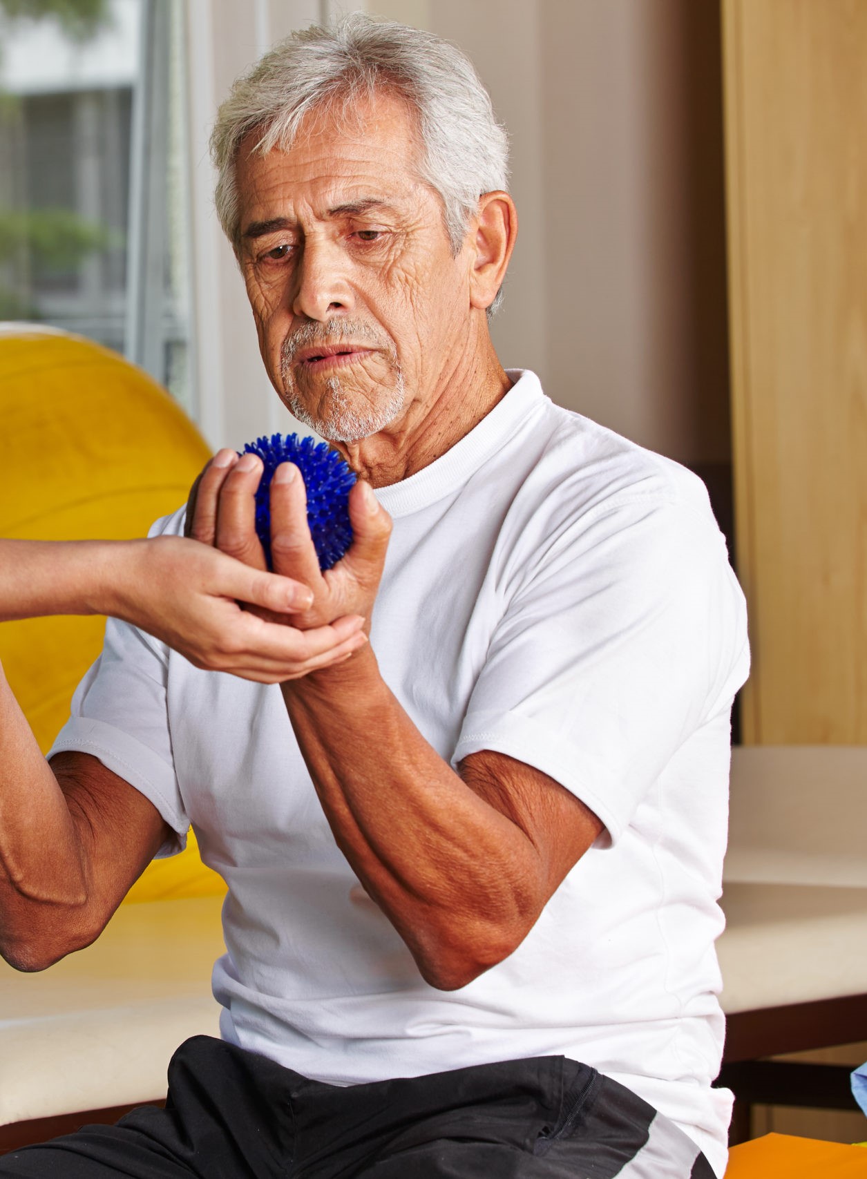 Senior man with spikey balls in gym with physiotherapist